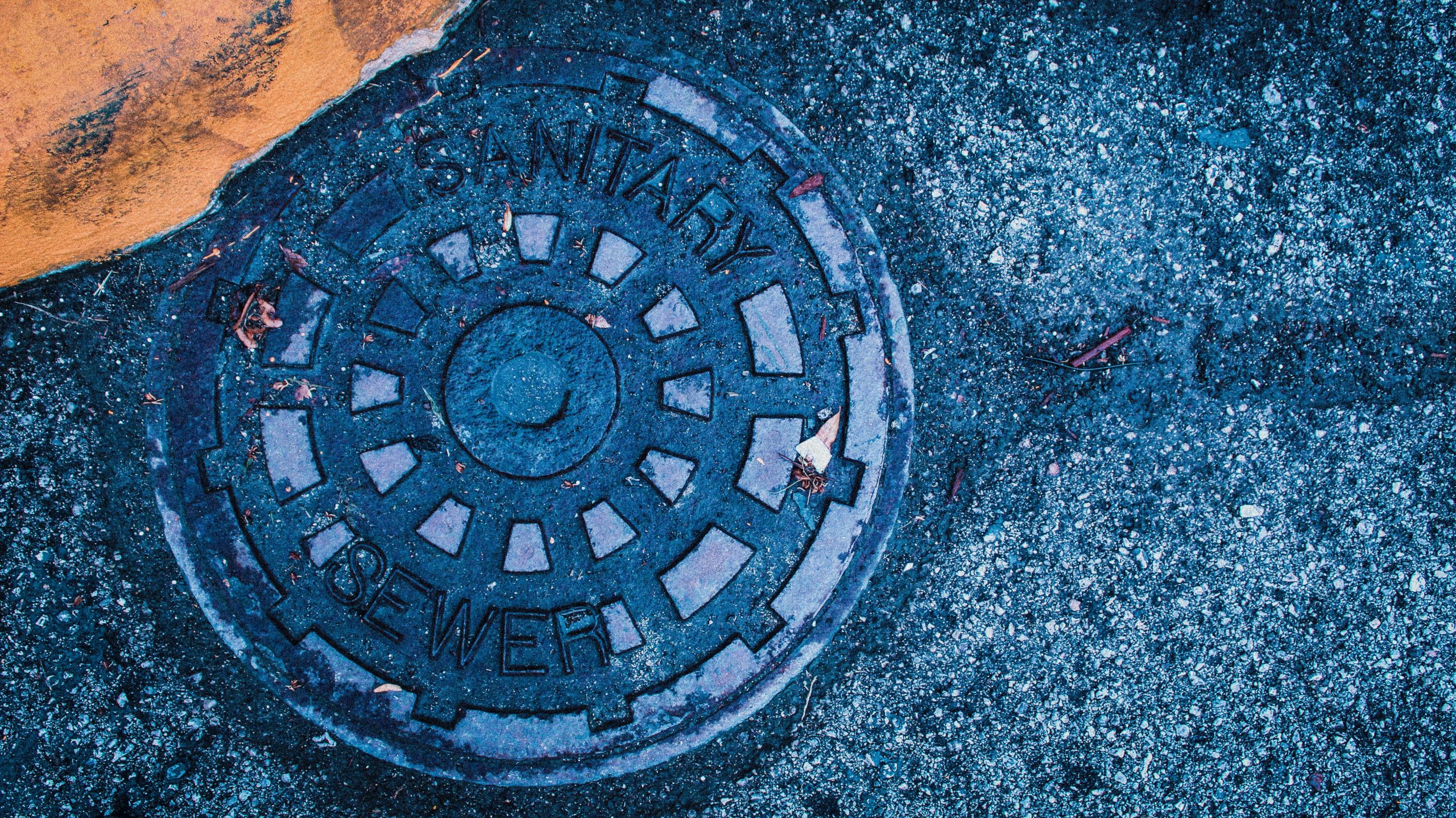 Sewer Drives Everything In Outdoor Resort Development 1 A manhole cover sitting flush with the pavement.